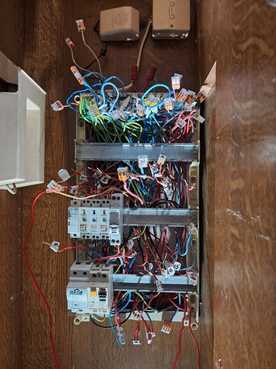 Vue de l'intérieur du tableau électrique lors de la rénovation à Annequin : enchevêtrement complexe de fils, neutres communs et raccordements anarchiques avant l'intervention de mise en conformité électrique.