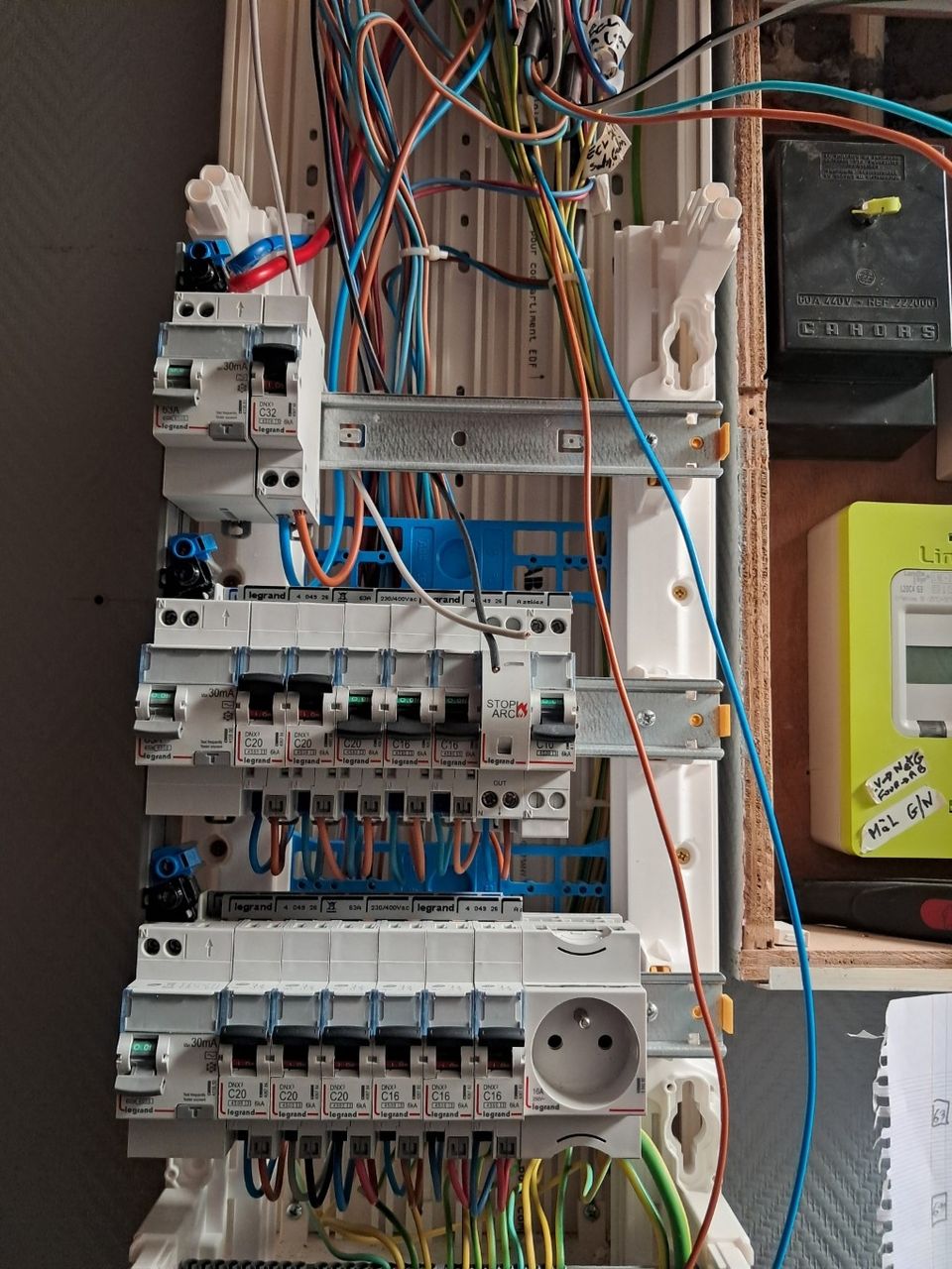 Gros plan sur l'amas de fils suspendus lors de la phase de câblage d'un nouveau tableau principal dans le cadre d'une rénovation électrique complète pour une maison ancienne à Armentières.